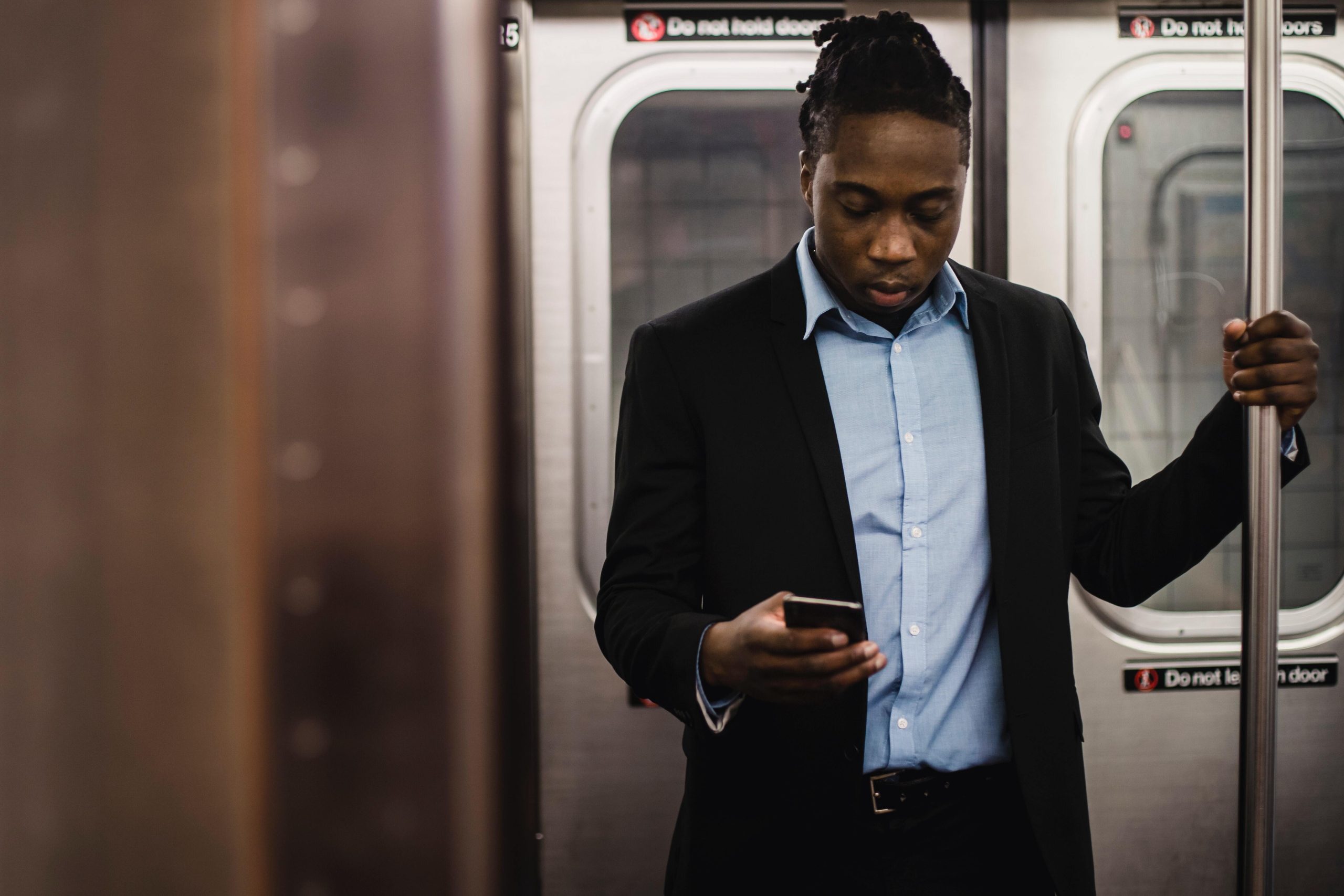 Man on a train reading a text message on a phone for bulk SMS with sender ID